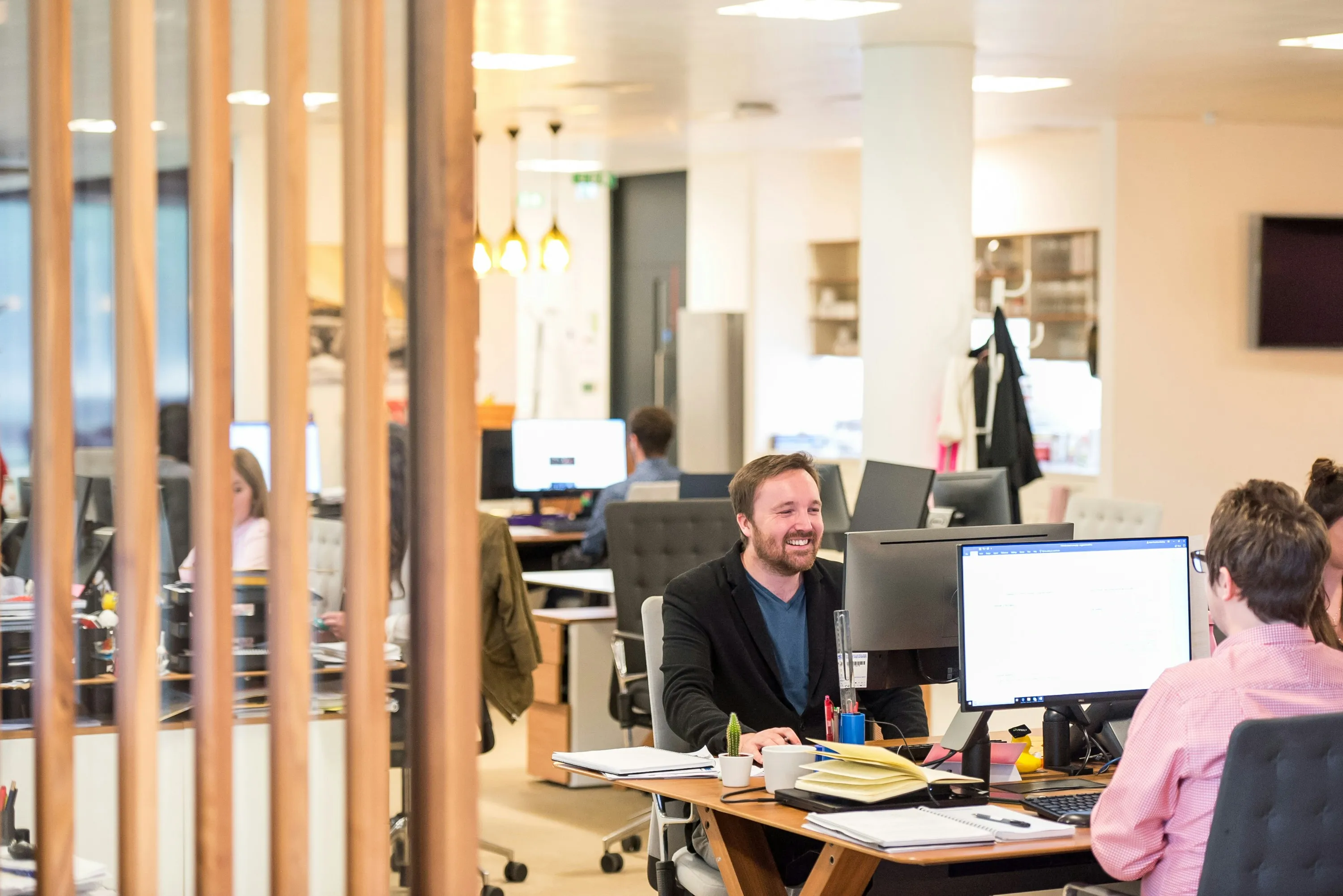 Équipe d'une PME nancéienne au travail dans des bureaux open-space modernes, ambiance détendue et productive grâce à une informatique qui tourne sans accroc